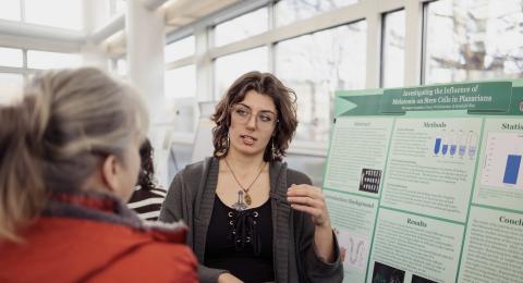 Student presents research at poster presentation.